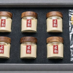 Guyun agarwood powder gift set open, six glass jars with walnut stoppers and red 古韵 seals beside a gold spoon in black foam