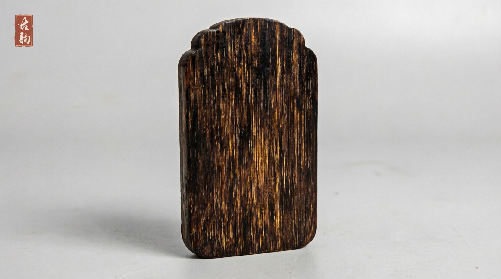 Plain reverse of the Guanyin agarwood amulet, showing natural oil lines running with the grain